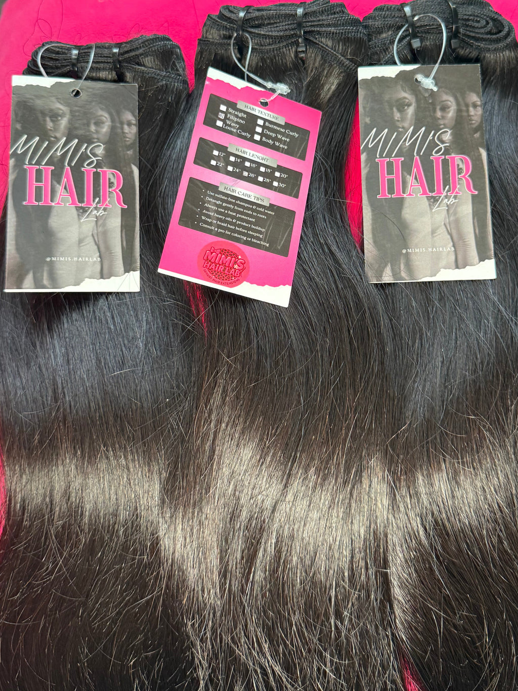 Hair extensions on a pink surface with visible brand labels.